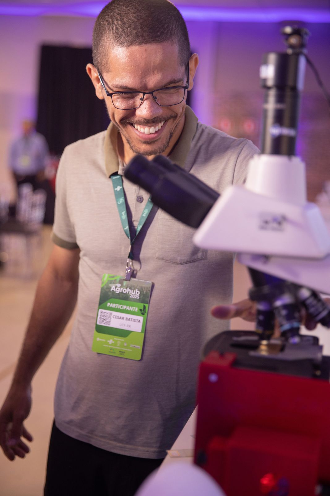 Participante sorrindo ao usar um microscópio